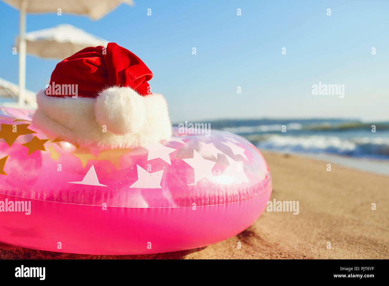 Santa Claus hat on the beach by the sea. Christmas on vacation b Stock