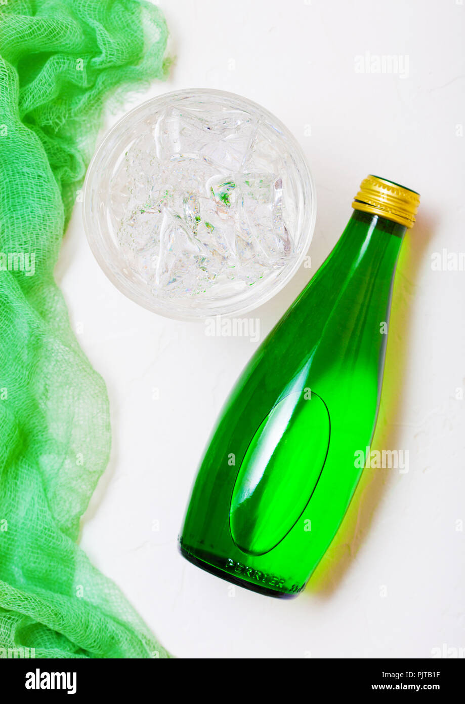 Bottle of sparkling mineral water with glass of ice and green cloth on ...