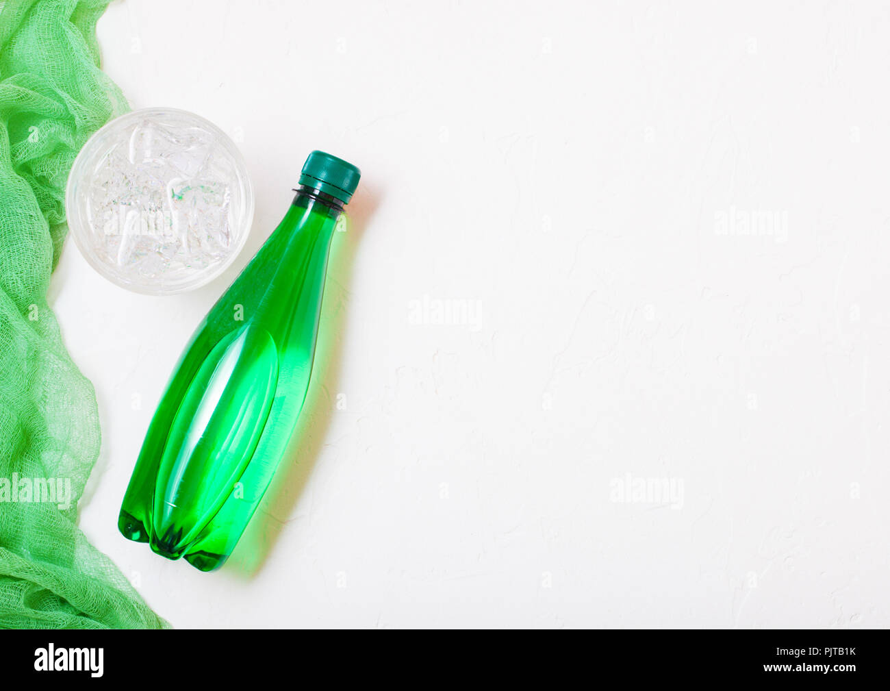 Bottle of sparkling mineral water with glass of ice and green cloth on ...
