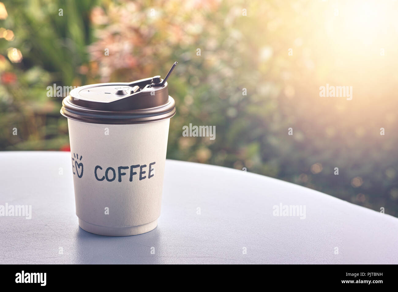 Hot Coffee in Paper coffee cup on table at morning time in the garden - vintage tone Stock Photo