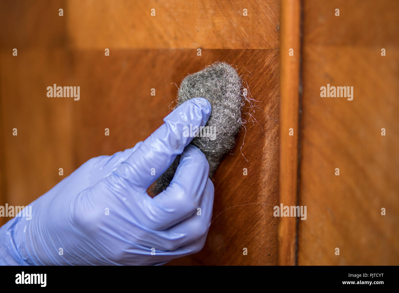 removing wax with steel wool as a part of restoration process of old