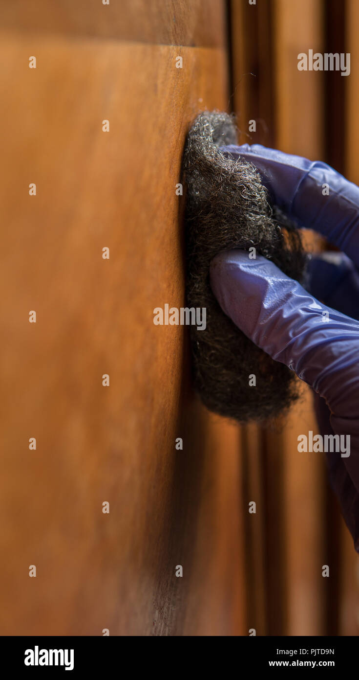 removing wax with steel wool as a part of restoration process of old