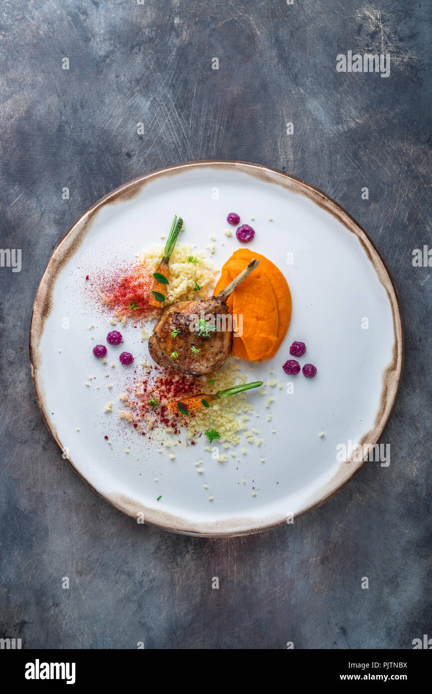 Duck leg confit with batat puree, carrots and couscous, restaurant meal, copy space Stock Photo