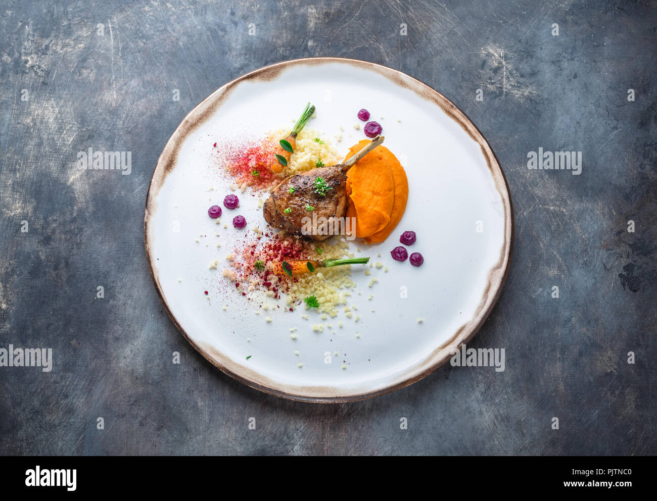 Duck leg confit with batat puree, carrots and couscous, restaurant meal Stock Photo