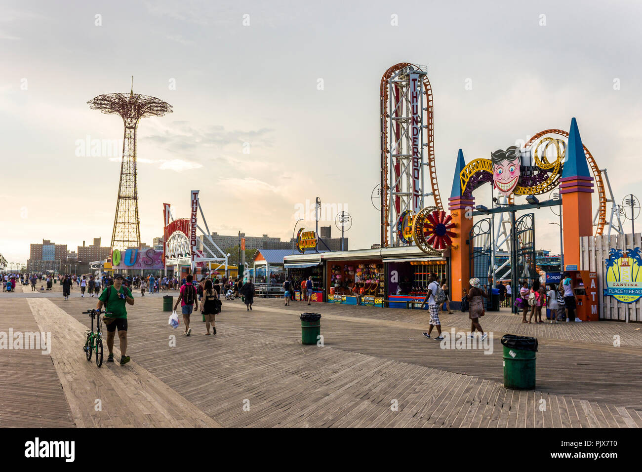 New York City. Views of Coney Island Promenade or Riegelmann Boardwalk on a busy summer day, with the Parachute Jump and the Thunderbolt in Luna Park Stock Photo