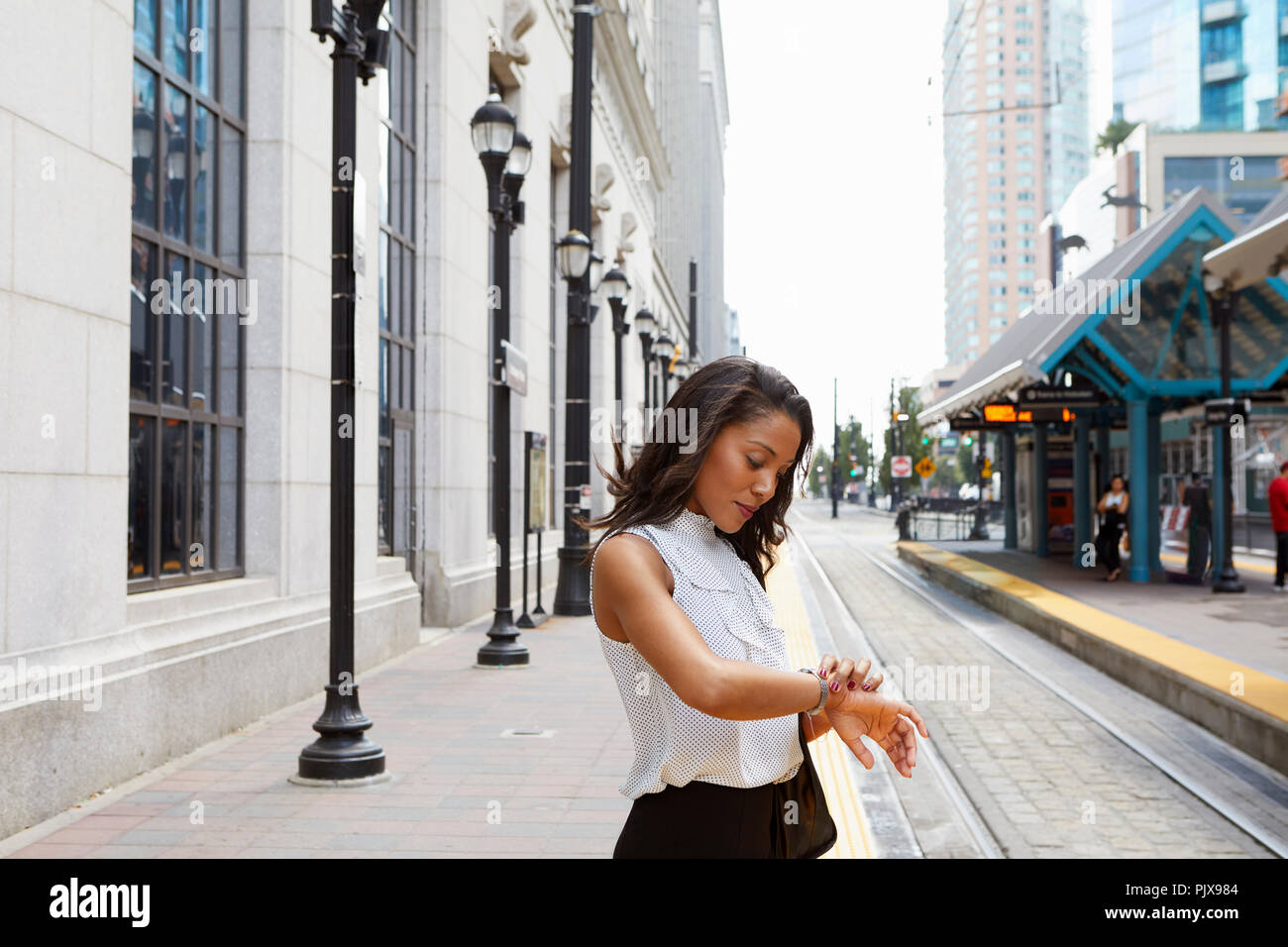Businesswoman checking time by light rail line Stock Photo