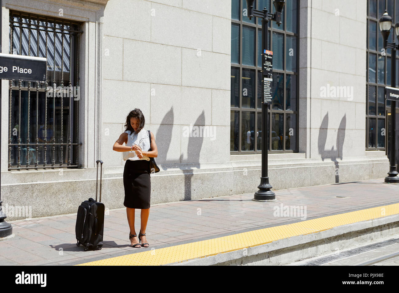 Businesswoman checking time by light rail line Stock Photo