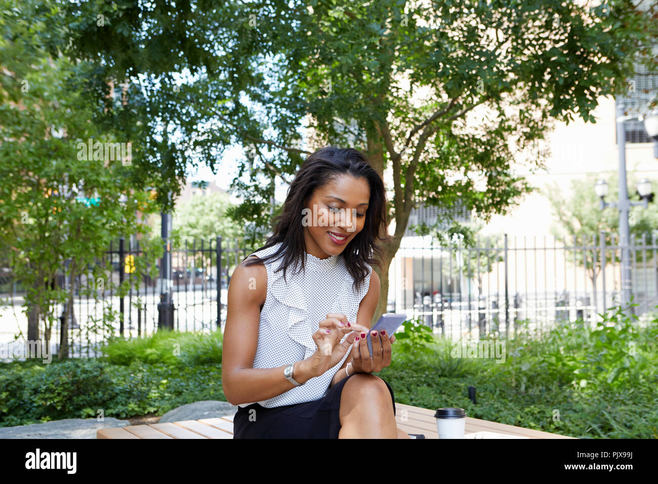 Businesswoman using cellphone in park Stock Photo