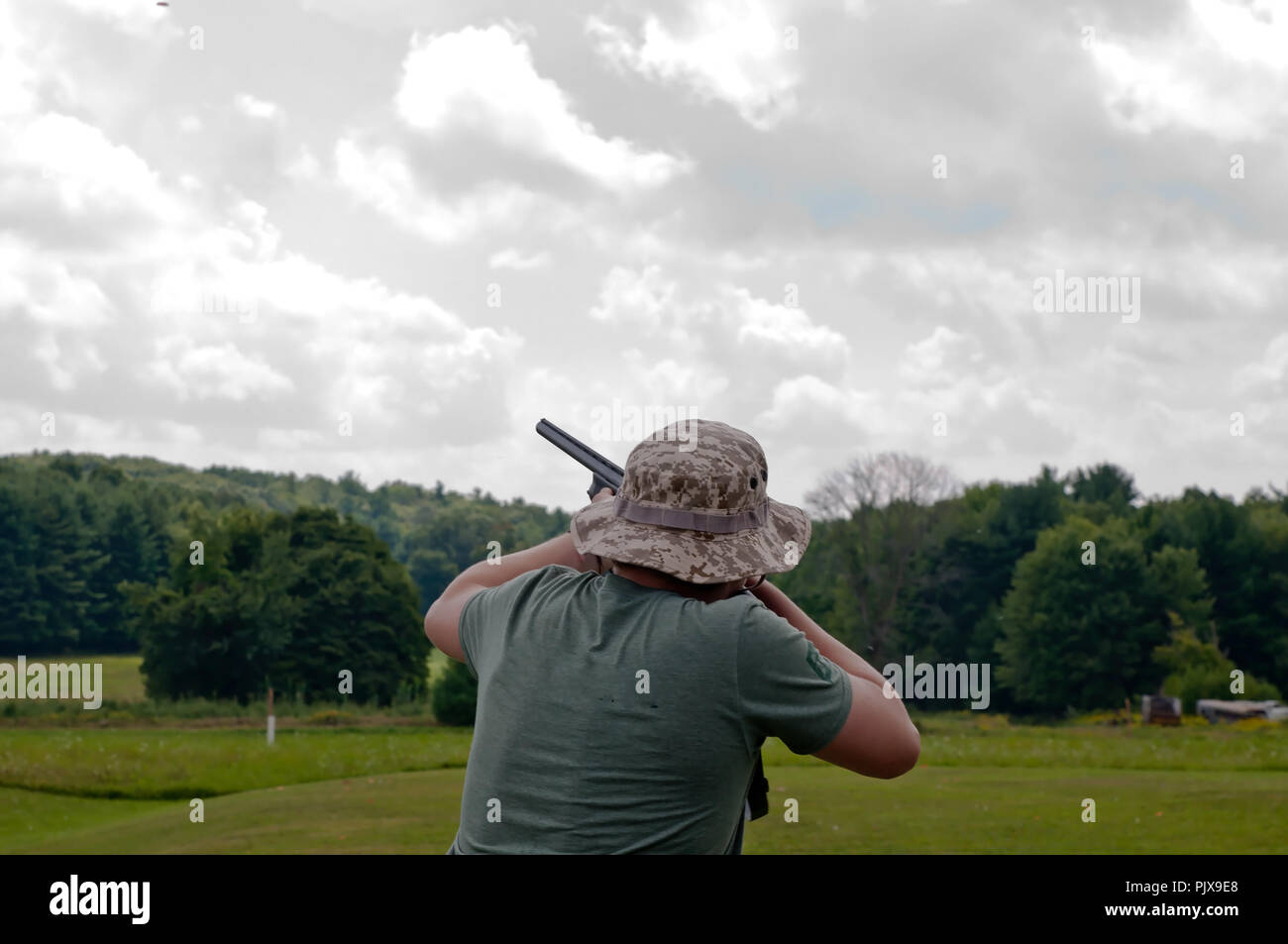A man trap shooting with a 12 gauge shotgun on a beautiful summer day at a gun club in northwest Pennsylvania, USA Stock Photo