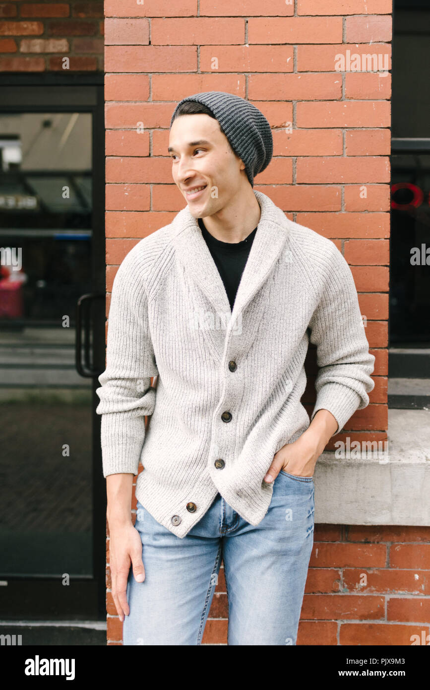Young man leaning against brick wall, Vancouver, Canada Stock Photo