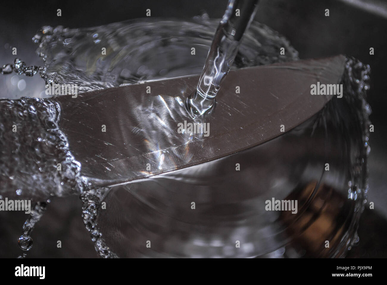 Washing a knife under a water stream Stock Photo