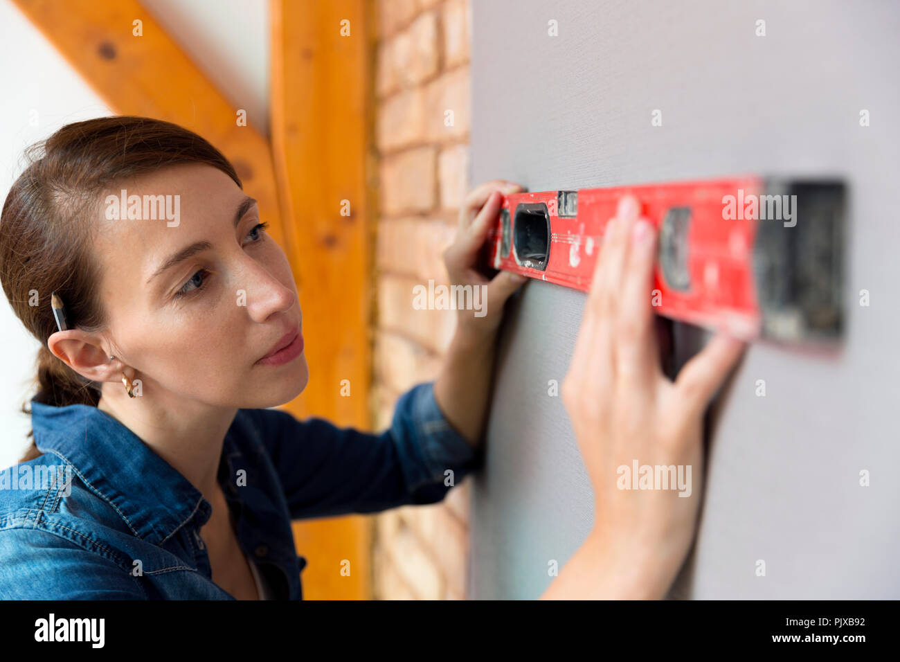 Home improvement. Beautiful women making a mark on wall with level. Stock Photo