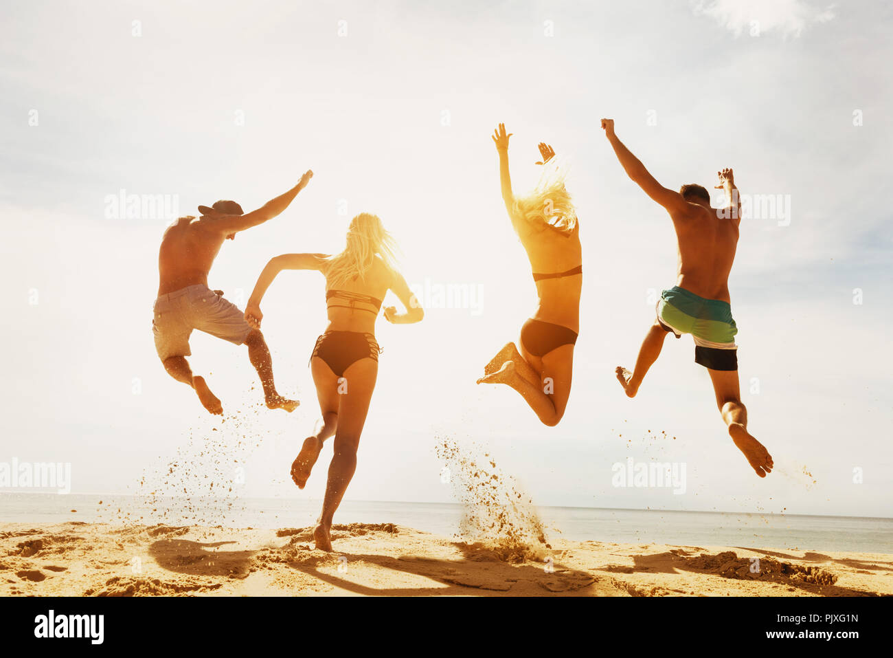 Happy friends sunset beach run jump Stock Photo