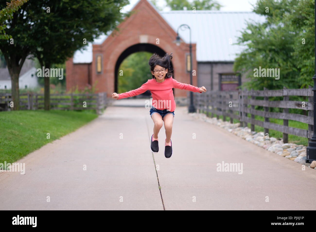 Smiling little Asian girl jump up in the park Stock Photo
