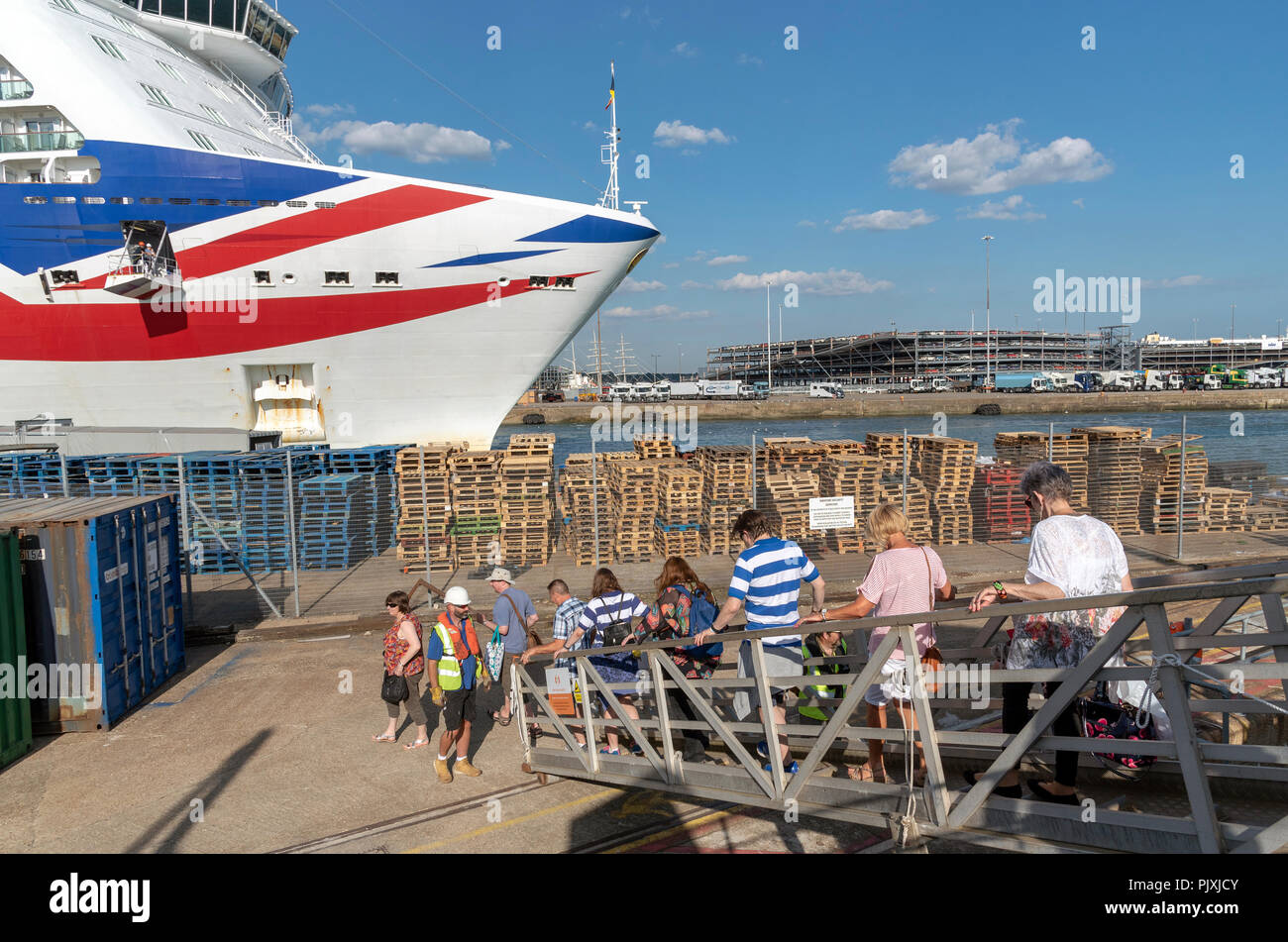 Ship's passengers arrive alongside port via a metal gangplank watched by a safety officer. A modern cruise ship in the background. Southampton, UK Stock Photo