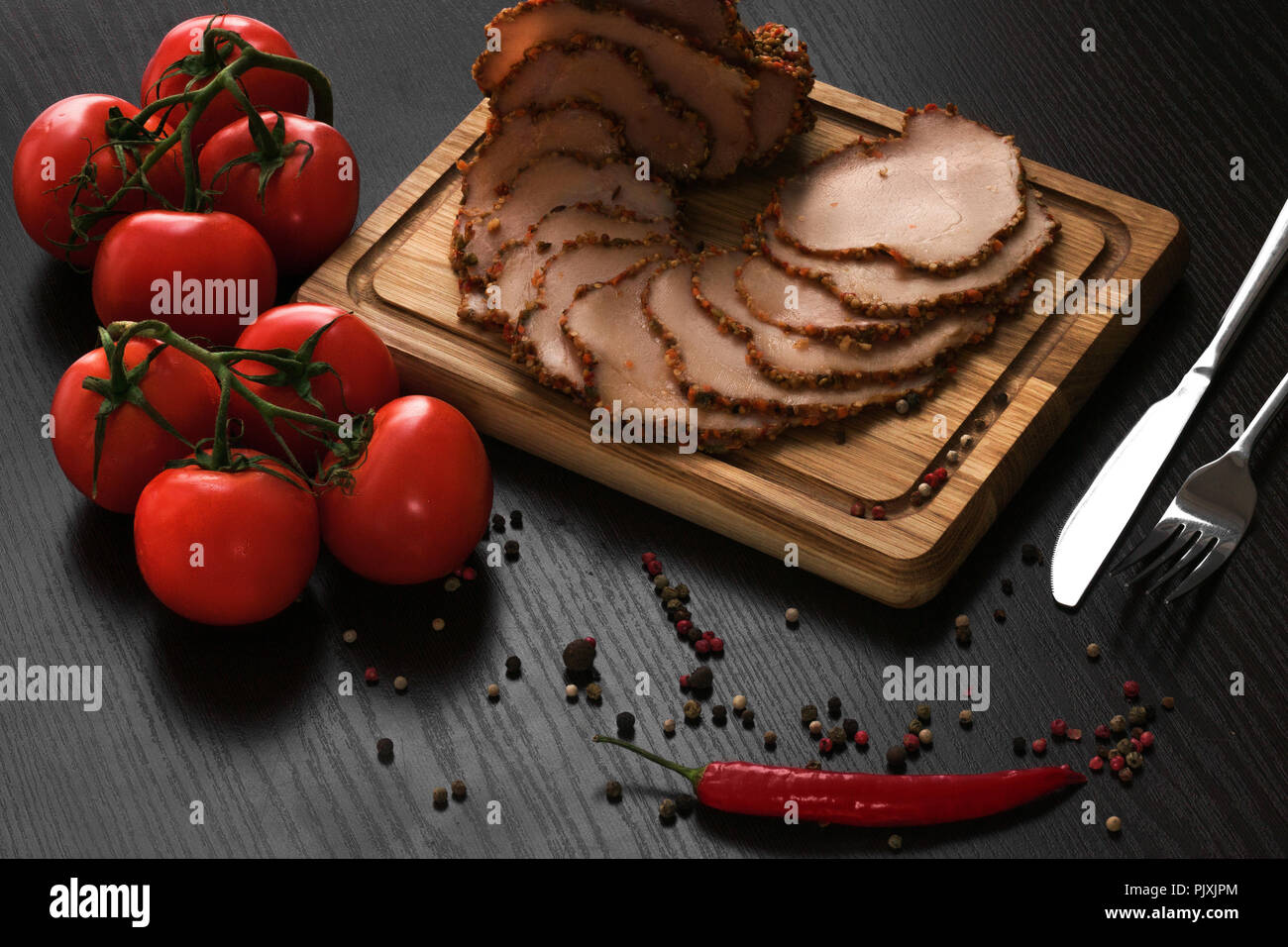Fresh ham with spices and tomatos on a black background Stock Photo