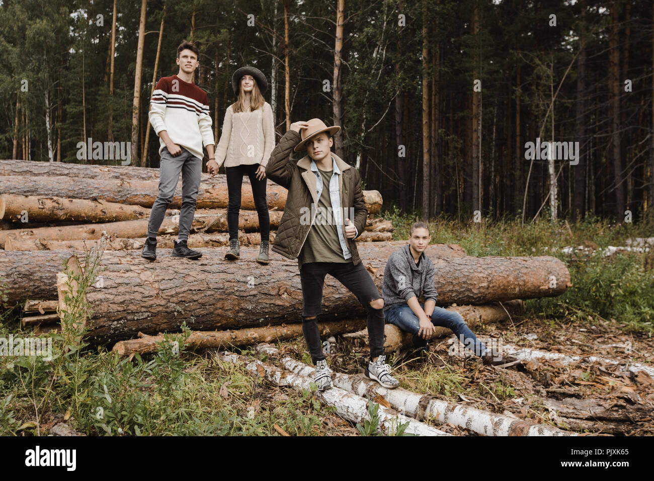 Group of young people standing on big logs Stock Photo