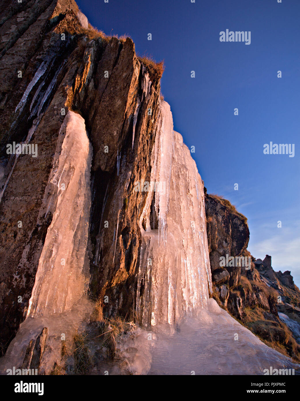 Frozen waterfall on Snowdon mountain in Snowdonia, North Wales, catching the light of the rising sun Stock Photo