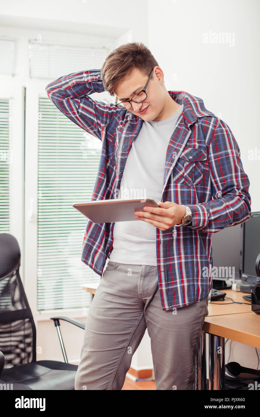 Worried young man is reading e-mail on  digital tablet while sitading in his office. Stock Photo