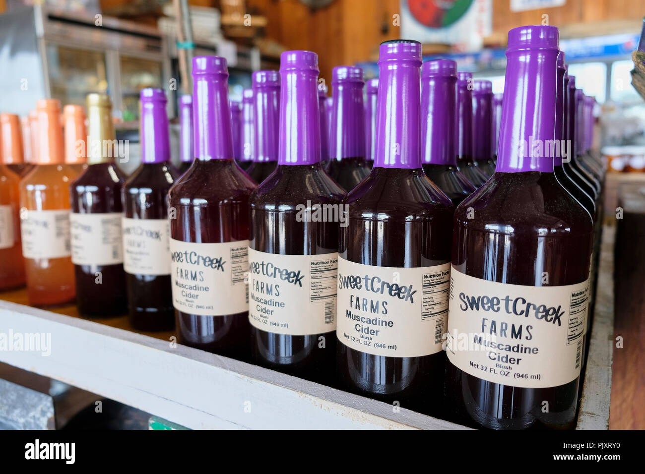 Colorful bottles of Muscadine Cider on a display shelf at the Sweet Creek Farm Market, a local rural farmer's market in Pike Road Alabama, USA. Stock Photo