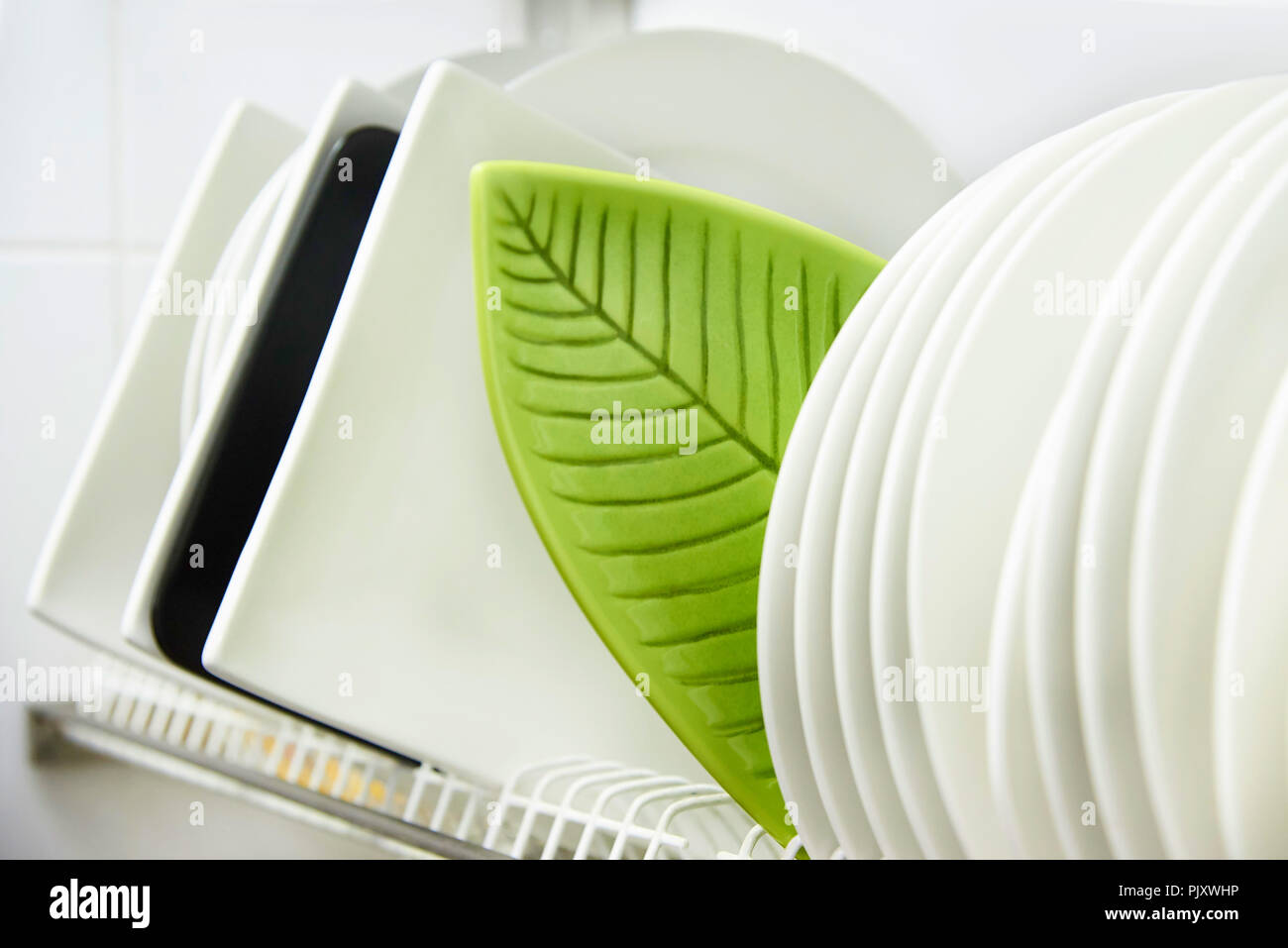 Different clean plates in dish drying rack close-up. Stock Photo