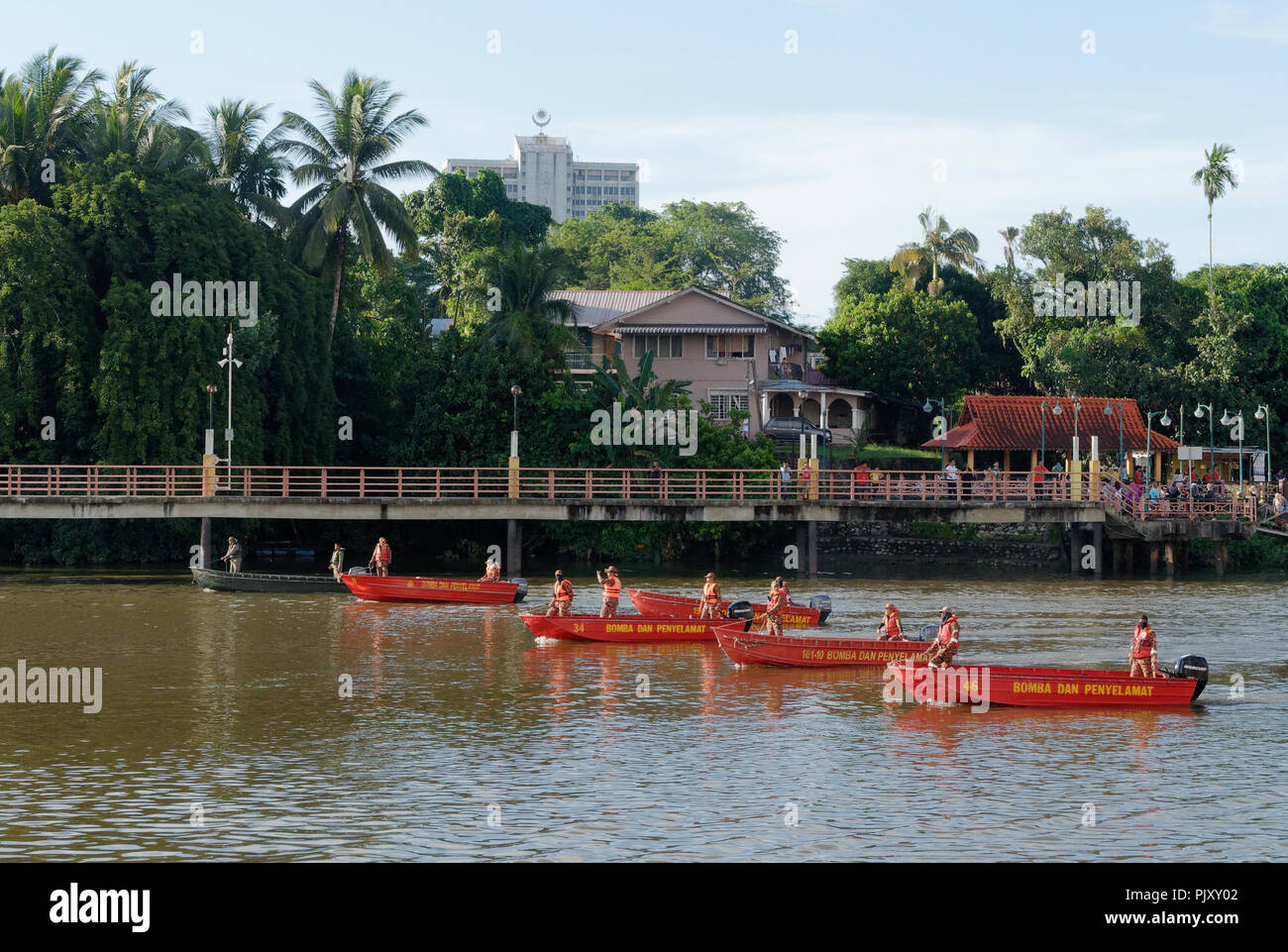 Kuching, Sarawak river, red boats with natives in fire fighers  form part of the Gawai day parade and celebration Stock Photo
