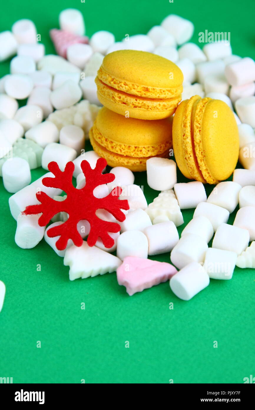 Yellow macaroons, marshmallow and red flake on green Stock Photo