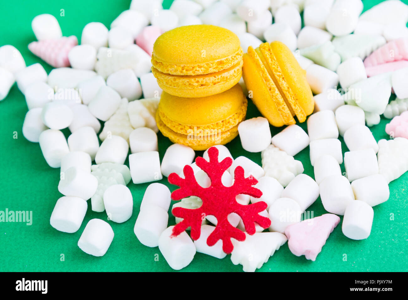 Yellow macaroons, marshmallow and red flake on green Stock Photo