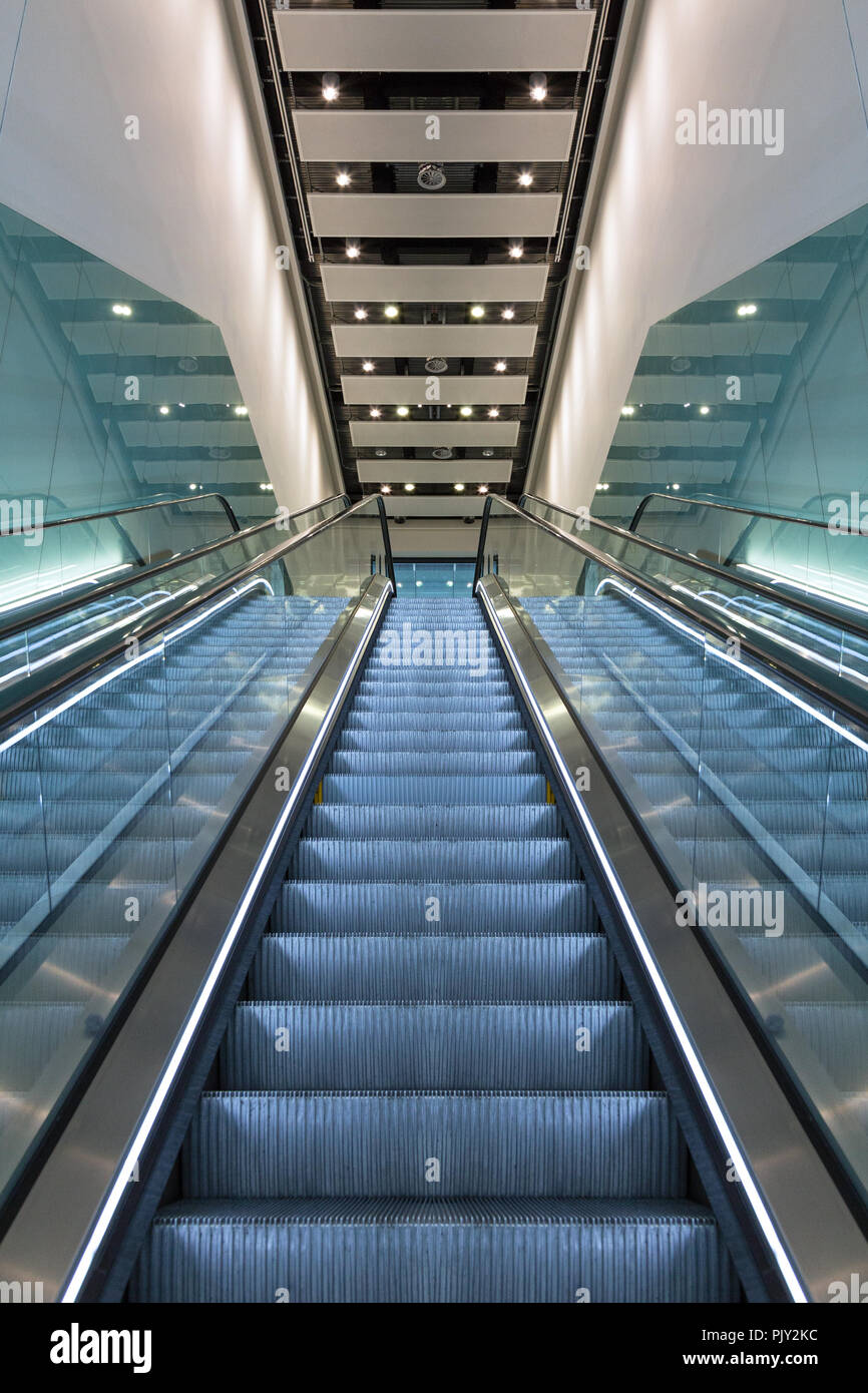 A modern escaltor with glass panels, looking from the bottom to the top. Stock Photo
