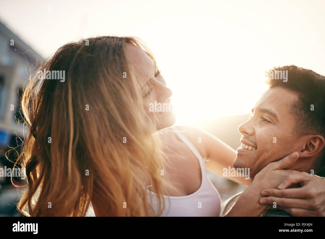 Smiling young woman being held in her boyfriend's arms while having fun together in the city Stock Photo