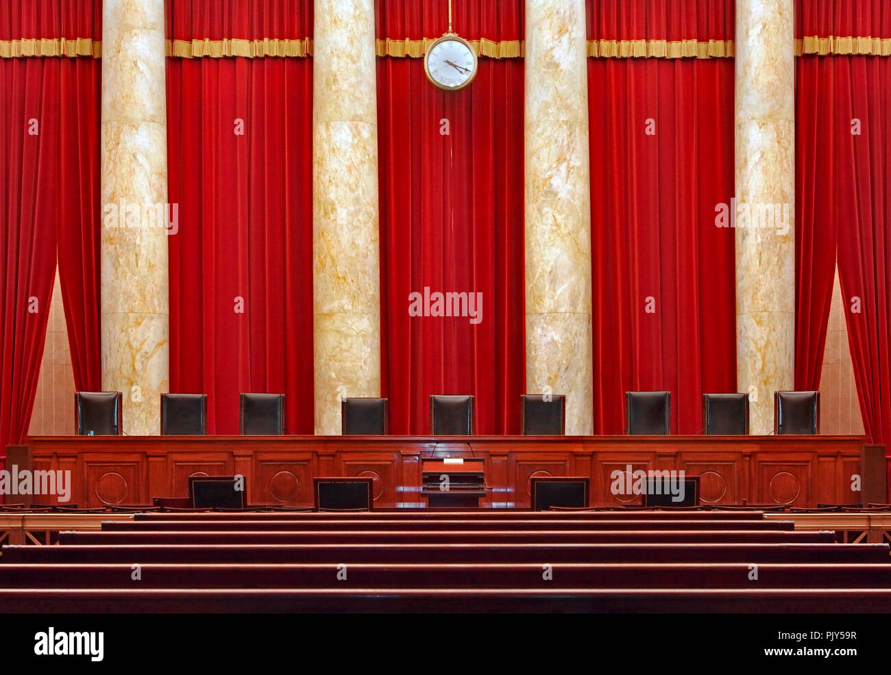 Court room interior at the United States Supreme Court, the seats for the nine powerful judges of the Supreme Court face the courtroom against a red b Stock Photo