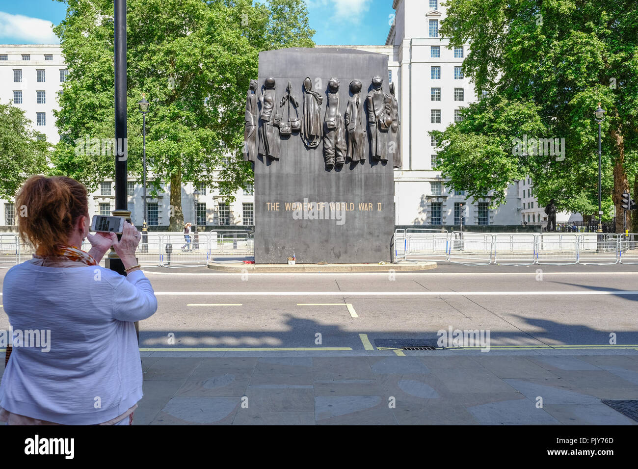 Whitehall, London, UK - June 8, 2018: Lady taking a photo with her mobile of the Monument for Women of World Ward Two memorial in Whitehall. Stock Photo