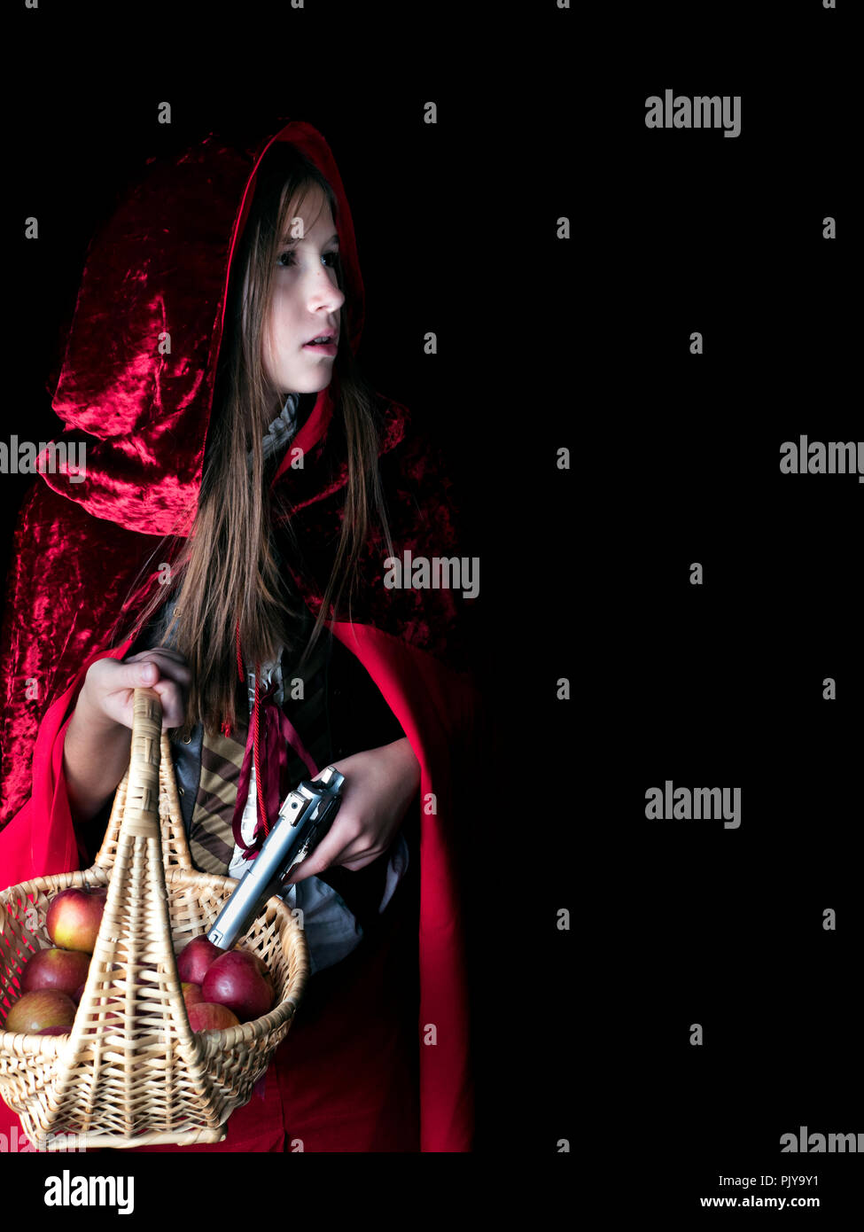 not-so-helpless little red riding hood, with an handgun dark night with a basket of apples for her grandma grandmother Stock Photo