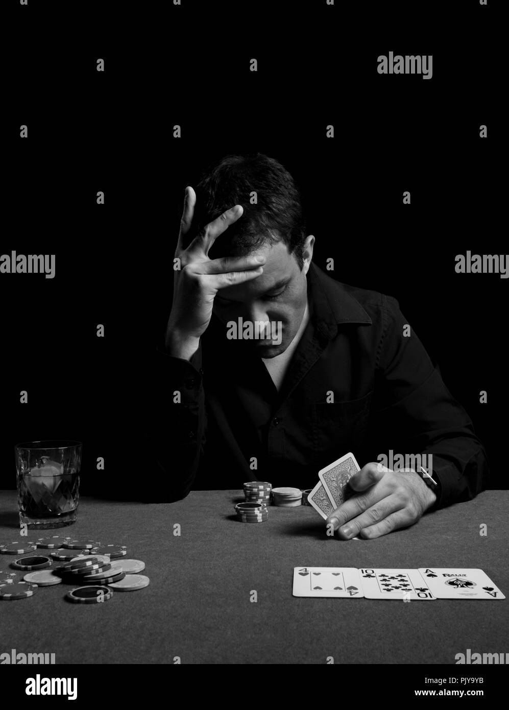 Concentrated man playin a game of poker texas hold'em looking at his cards tension tense tensed Stock Photo
