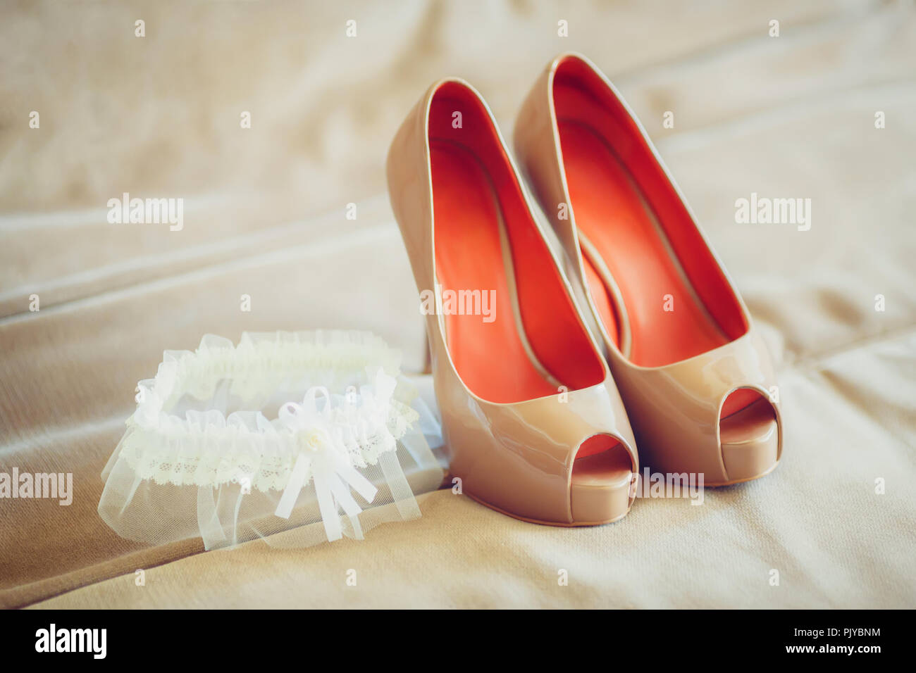 Beige wedding bridal shoes with garter on sofa marriage concept Stock Photo Alamy