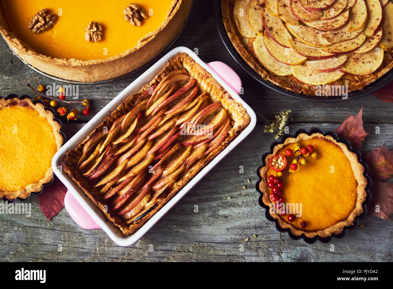 autumn background, homemade pumpkin and apple pie with autumn decoration over wooden rustic table Stock Photo