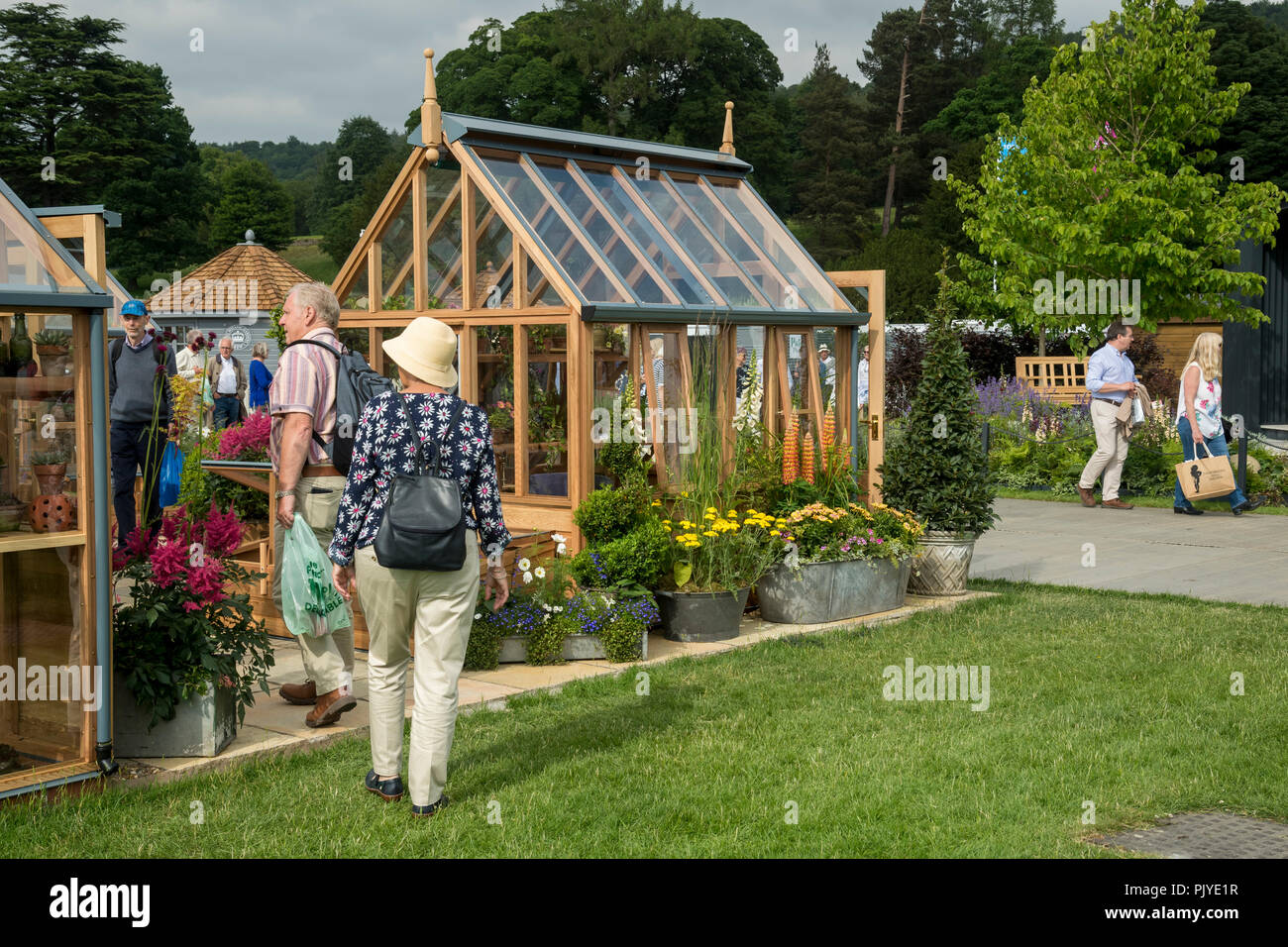 People walking & having a look at greenhouses displayed & for sale on attractive trade stand - RHS Chatsworth Flower Show, Derbyshire, England, UK. Stock Photo