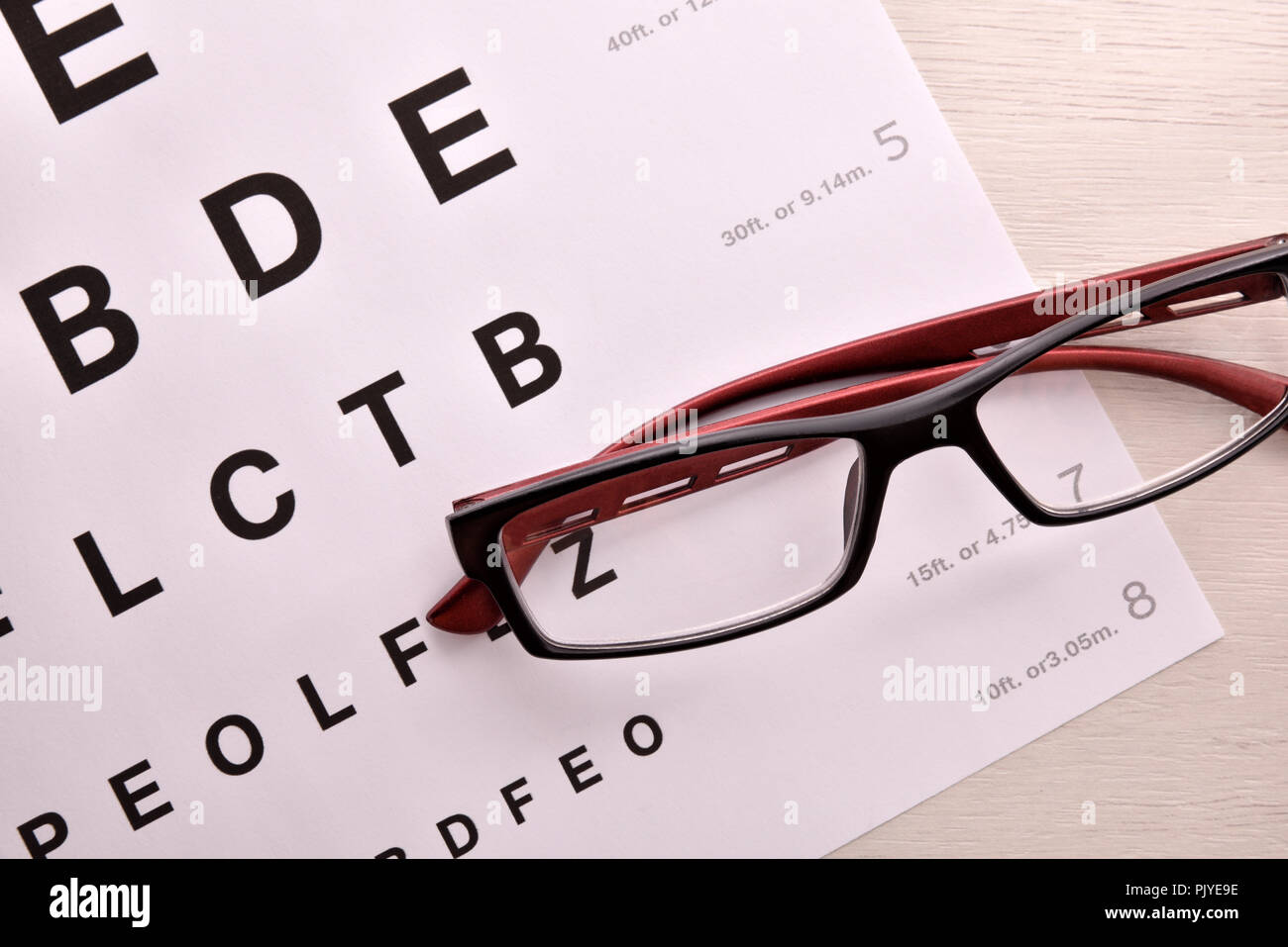 Concept of eye revision with sheet with letters and correction glasses. Top view. Horizontal composition Stock Photo