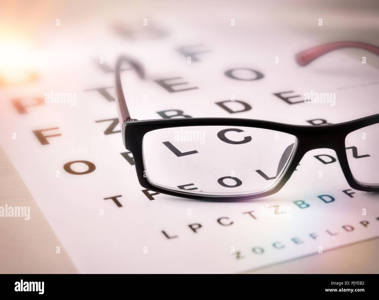 Concept of eye revision with sheet with letters and correction glasses. Elevated view. Horizontal composition Stock Photo