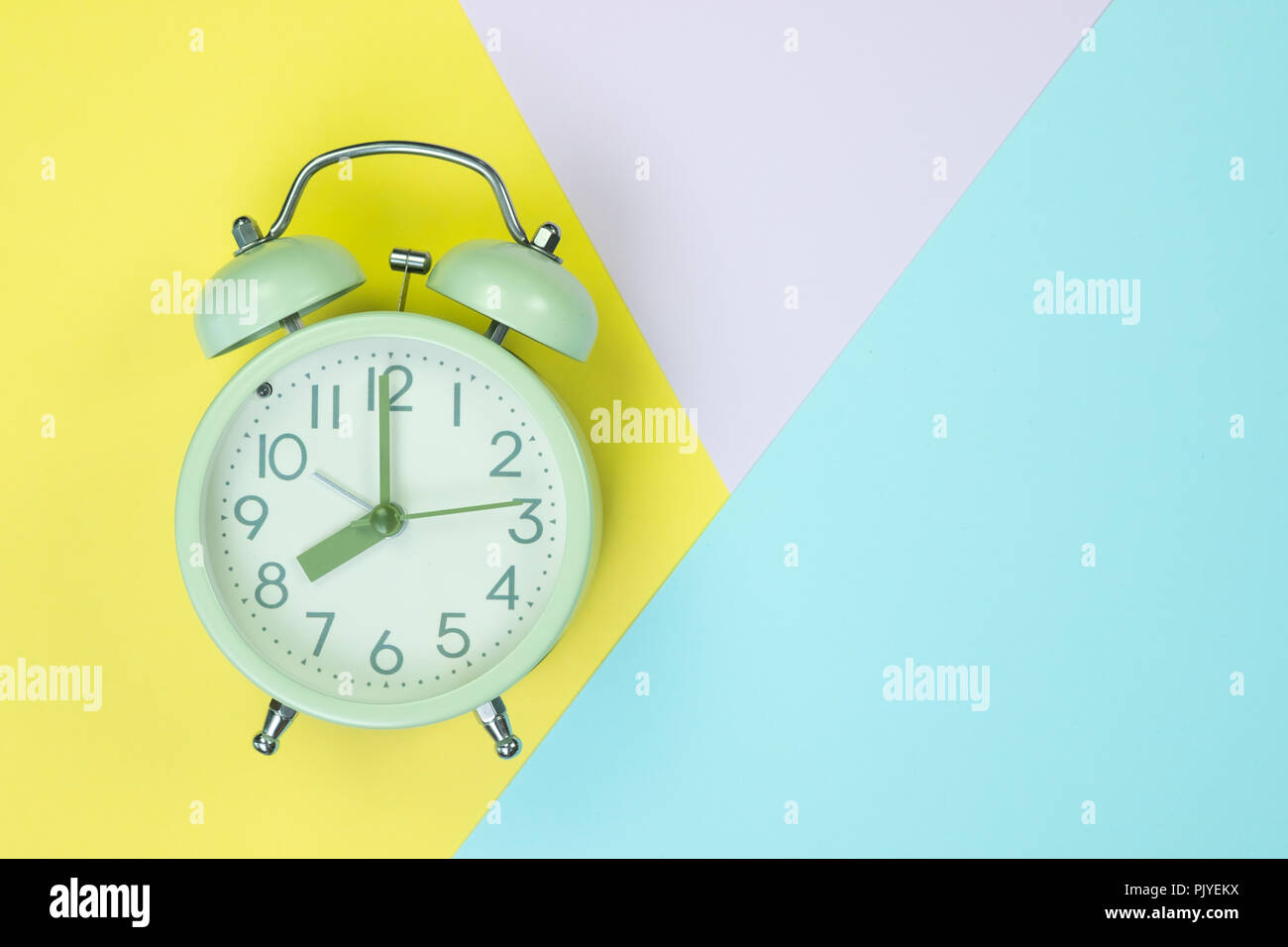 Flat lay vintage alarm clock on sweet pastel colored paper top view ...