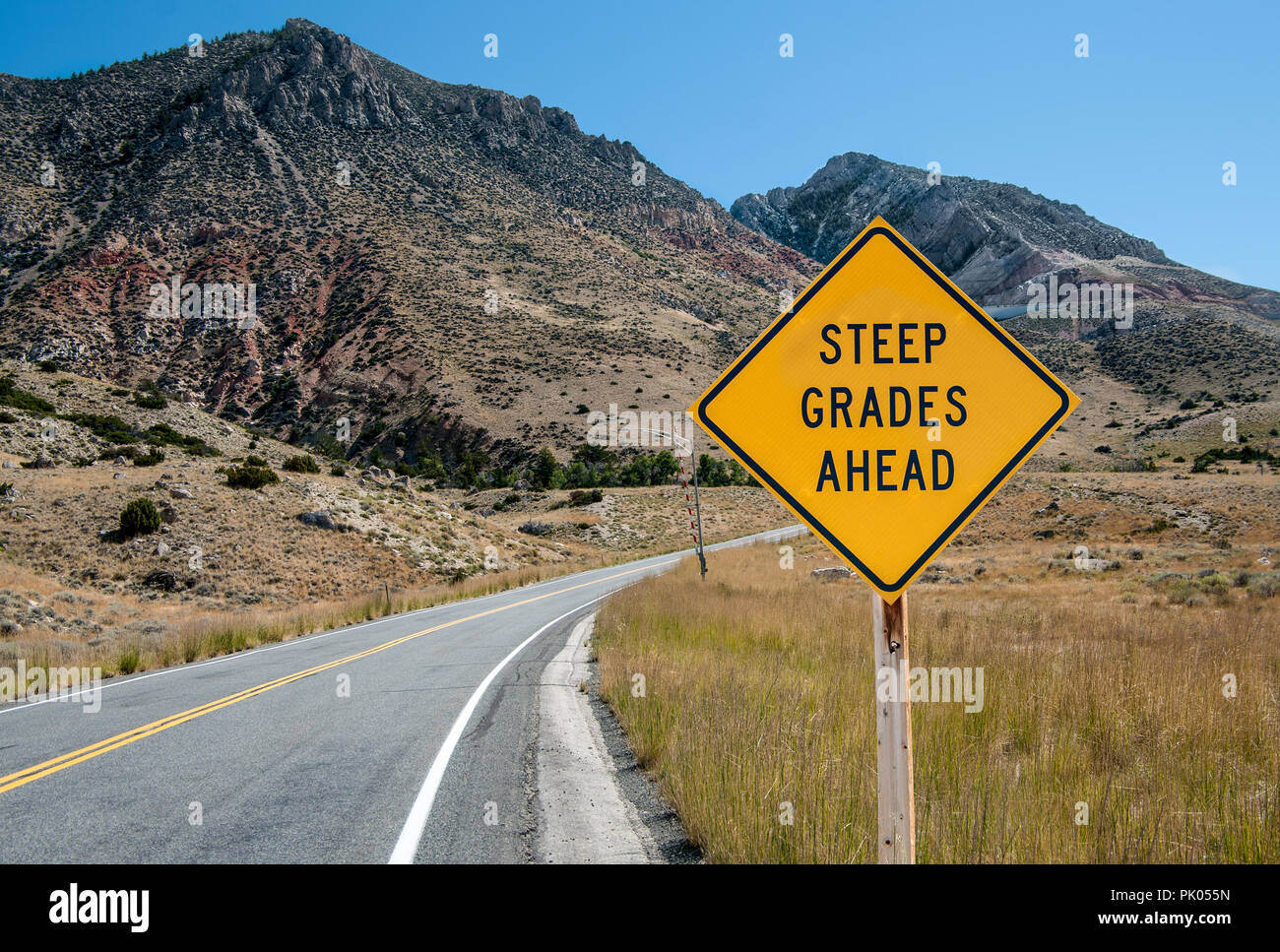 Steep Grades Warning Sign:  A sign warns of a steep climb ahead on a road leading into the Big Horn Mountains of northeastern Wyoming. Stock Photo