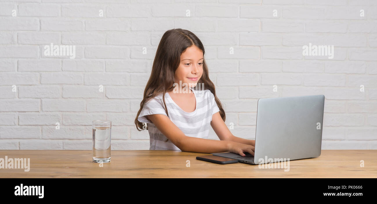 Young hispanic kid sitting on the table using computer laptop with a ...