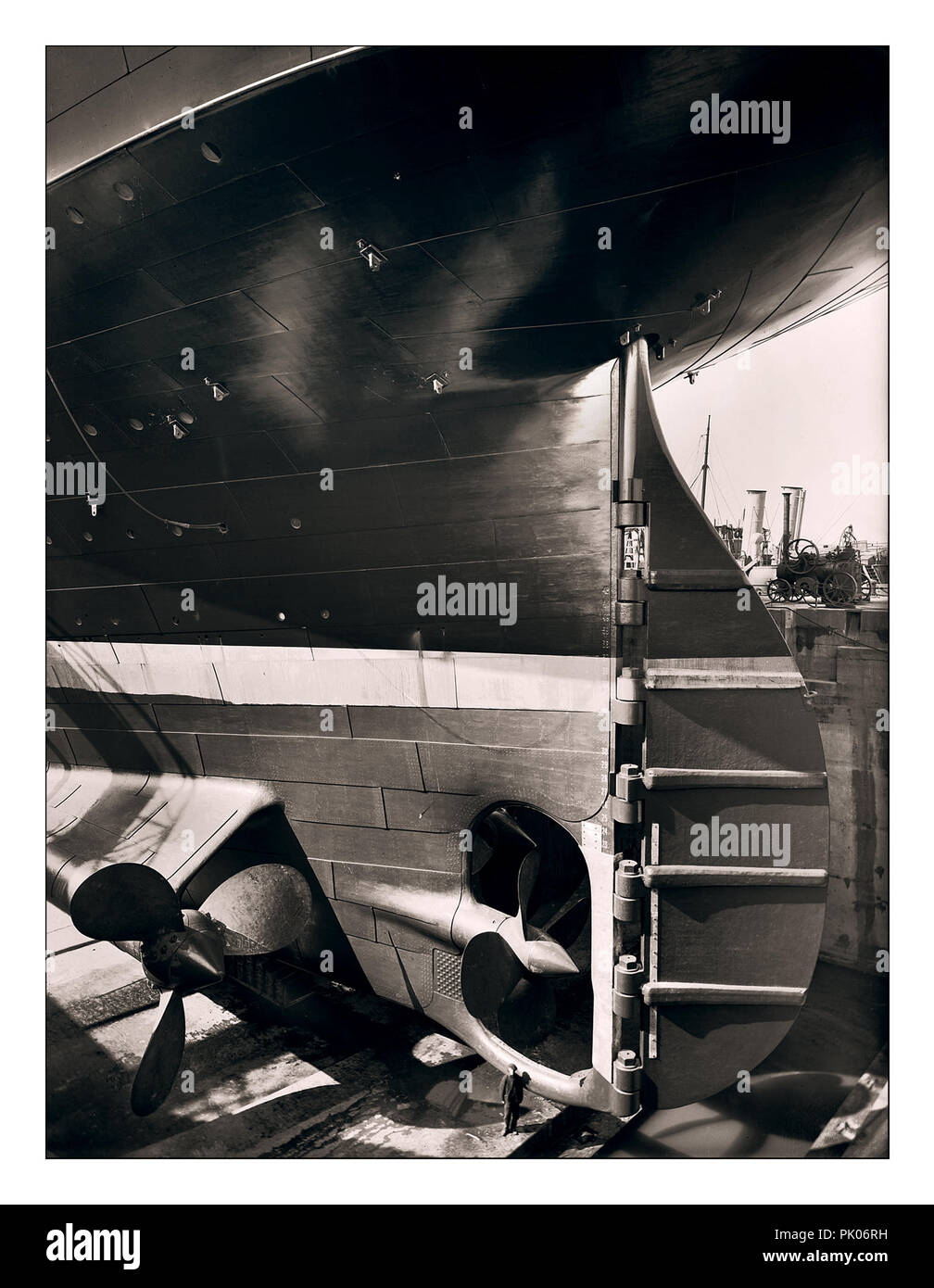 TITANIC STERN WORKER SIZE CONSTRUCTION Historic 1912 image of RMS Titanic rudder and propellors with ship worker in the huge dry dock construction site adding scale to the huge Ocean Liner Harland and Wolff shipyard Belfast UK Stock Photo