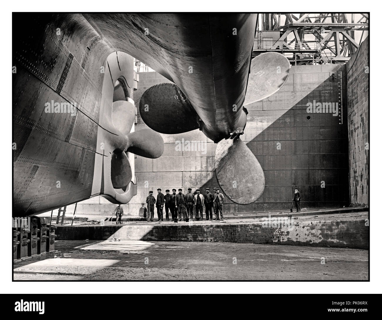 TITANIC/OLYMPIC PROPELLOR  Historic ship build 1912 image of RMS Titanic rudder and propellors with group of ship workers in the huge dry dock construction site adding scale to the huge Ocean Liner. Harland and Wolff shipyard Belfast UK Stock Photo