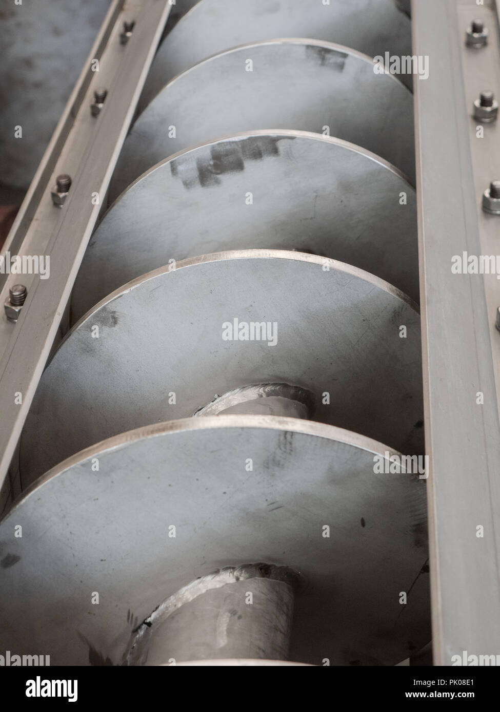 Detail of stainless steel screw conveyor for a food processing plant. Stock Photo