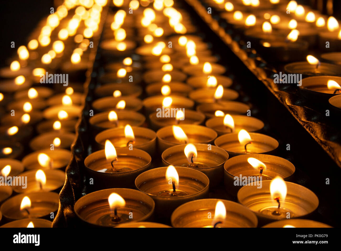 Many beautiful lit candles in a row glowing with a golden yellow light