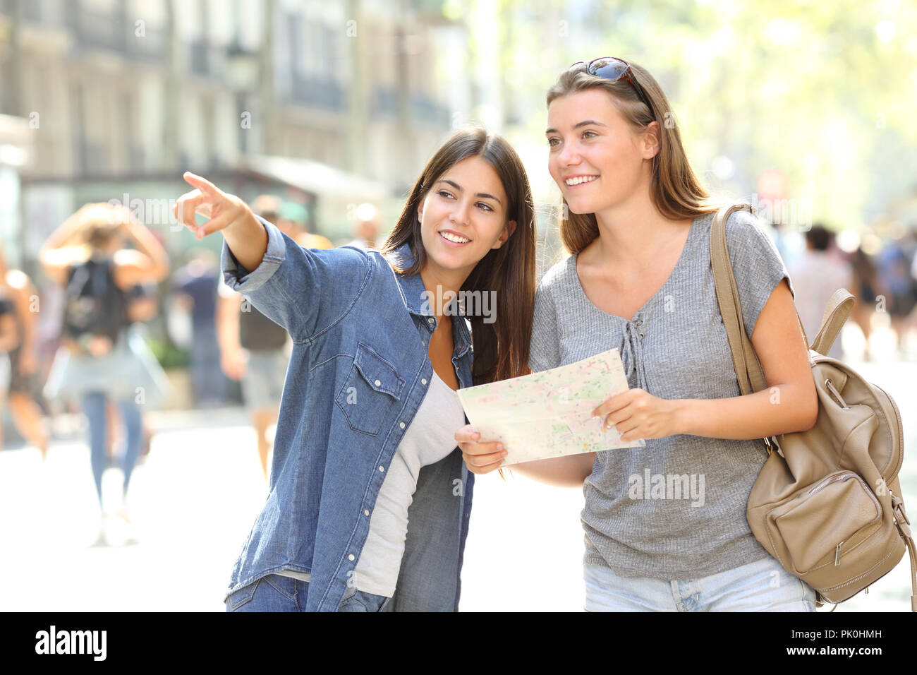 Happy girl helping to a tourist who asks direction in the street Stock Photo