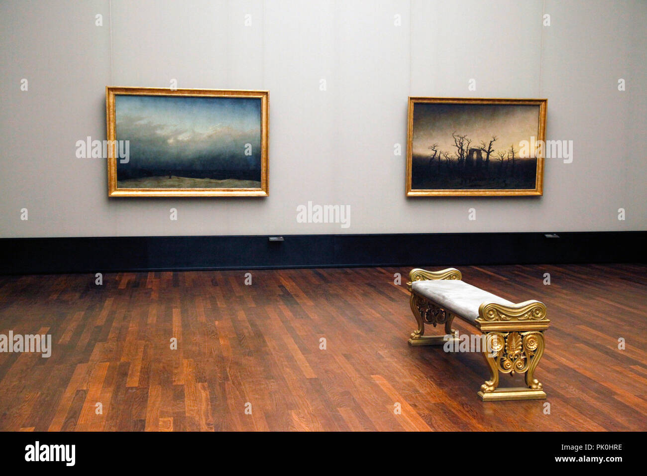 A lone ornate gilded viewing bench sits empty in vacant gallery of paintings feeling romantic yet forlorn in the National Gallery in Berlin, Germany Stock Photo