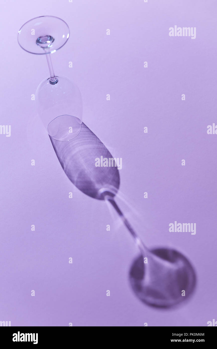 Inverted empty wine glass with reflection of shadow on purple ...