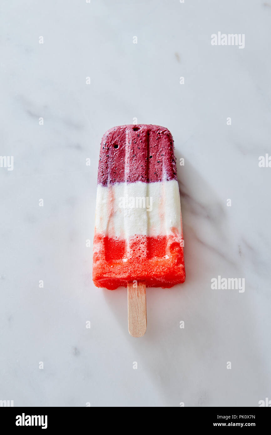 Tricolor fruit and berries ice cream on wooden stick sitting on a marble  background, top view Stock Photo - Alamy